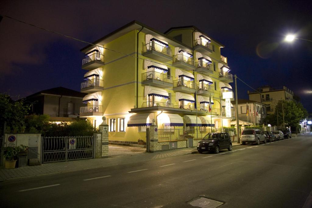 un gran edificio amarillo con coches estacionados frente a él en Hotel Fortunella, en Lido di Camaiore