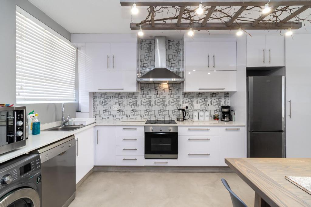 a kitchen with white cabinets and a stove top oven at Albetros 904 in Amanzimtoti
