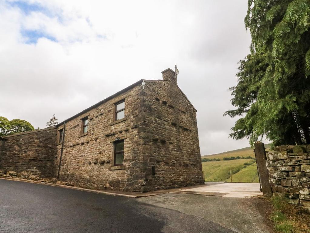 ein altes Steingebäude am Straßenrand in der Unterkunft Garth Gill in Sedbergh