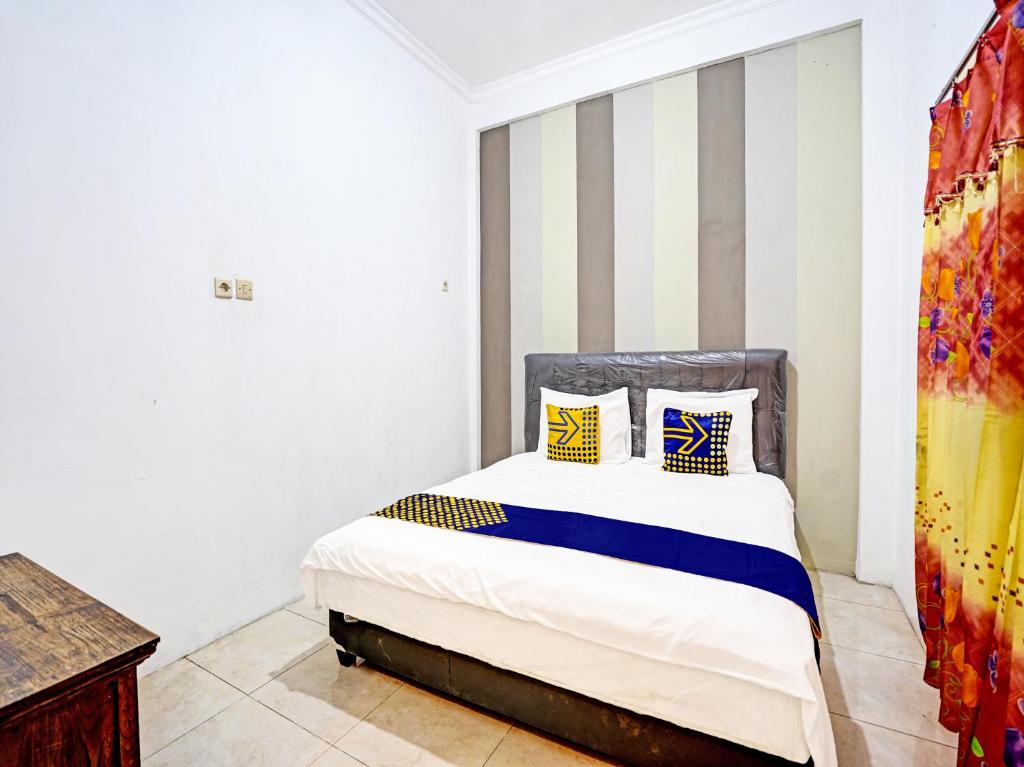 a bedroom with a bed with a striped wall at OYO 90943 Mochi 88 Homestay in Probolinggo