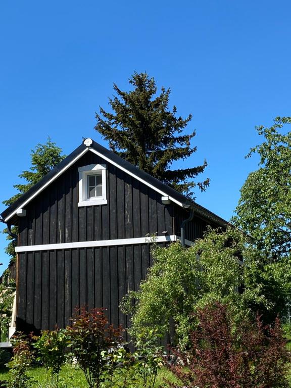 a black house with a window on the side of it at Domek TRZY BABY in Dołgie