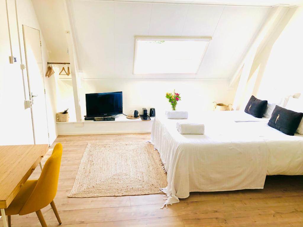 een witte slaapkamer met een bed en een televisie bij B&B in woonboerderij vlakbij Lemmer in Rutten