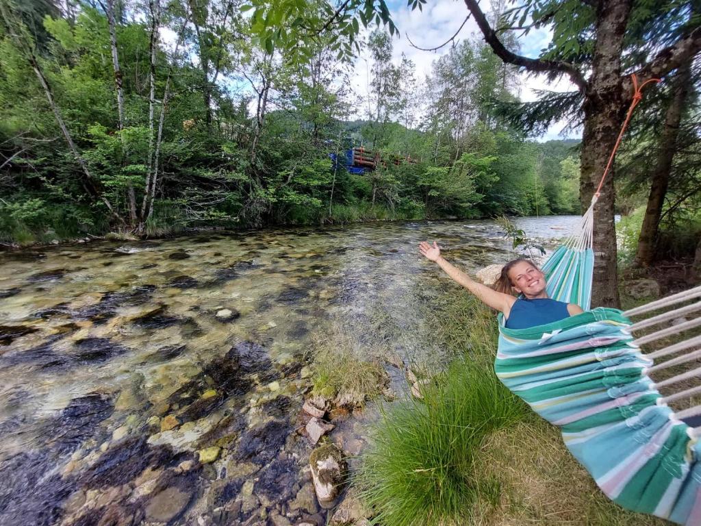 una mujer tendida en una hamaca junto a un río en The RiverSide Chill Hostel, en Zgornje Gorje