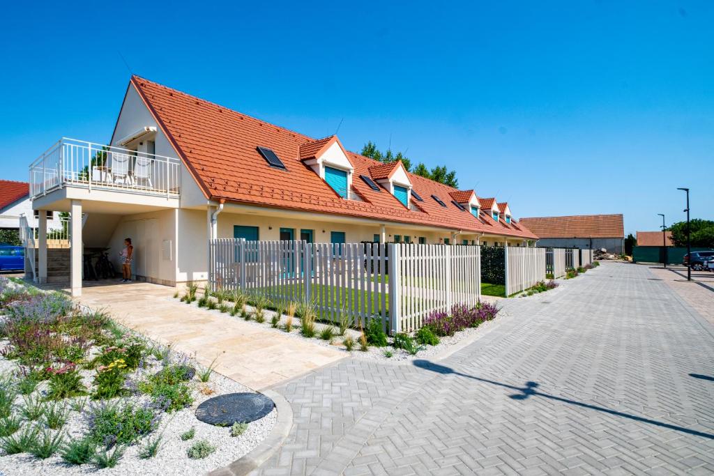 una casa con techo naranja y una valla blanca en Apartmány Na Zahradách, en Lednice