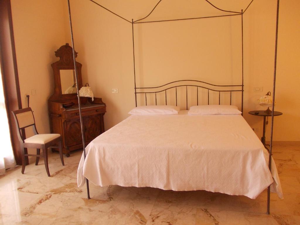 um quarto com uma cama grande e uma cadeira em Villa Costanza em Bobbio