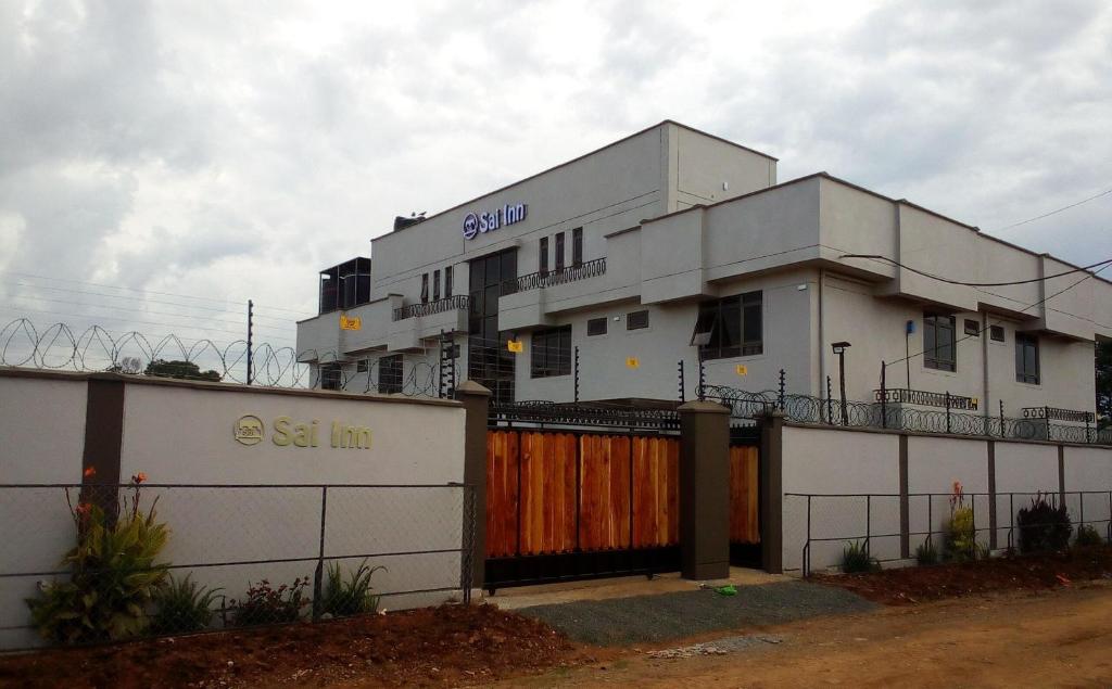 a white building with a fence in front of it at Sai Inn Eldoret in Eldoret