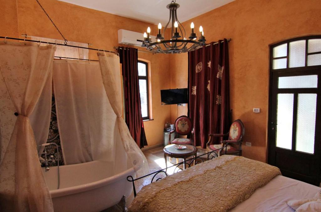 1 dormitorio con bañera, cama y lámpara de araña en Atelier Luxury Rooms, en Haifa