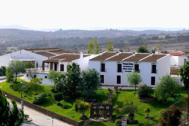 un gran edificio blanco con un patio verde en POSADA LOS PEDREGALES en El Granado