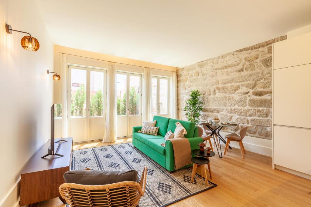 een woonkamer met een groene bank en een bakstenen muur bij D&S - Lazaros Apartments in Porto