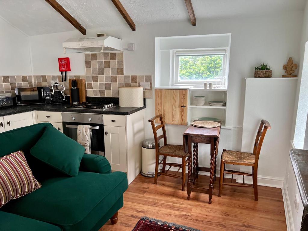 ein Wohnzimmer mit einem grünen Sofa und einer Küche in der Unterkunft Little Withens in Haworth