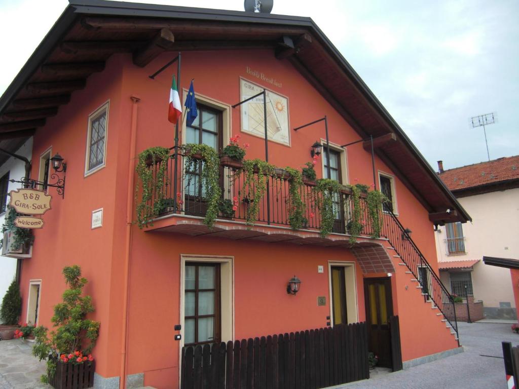 un edificio rojo con balcón y banderas. en B&B Gira-Sole, en Cuneo