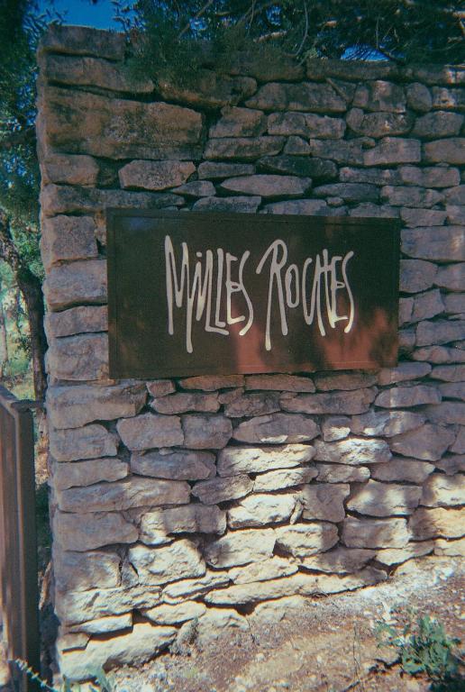 a sign on the side of a stone wall at Les Milles Roches in Gordes
