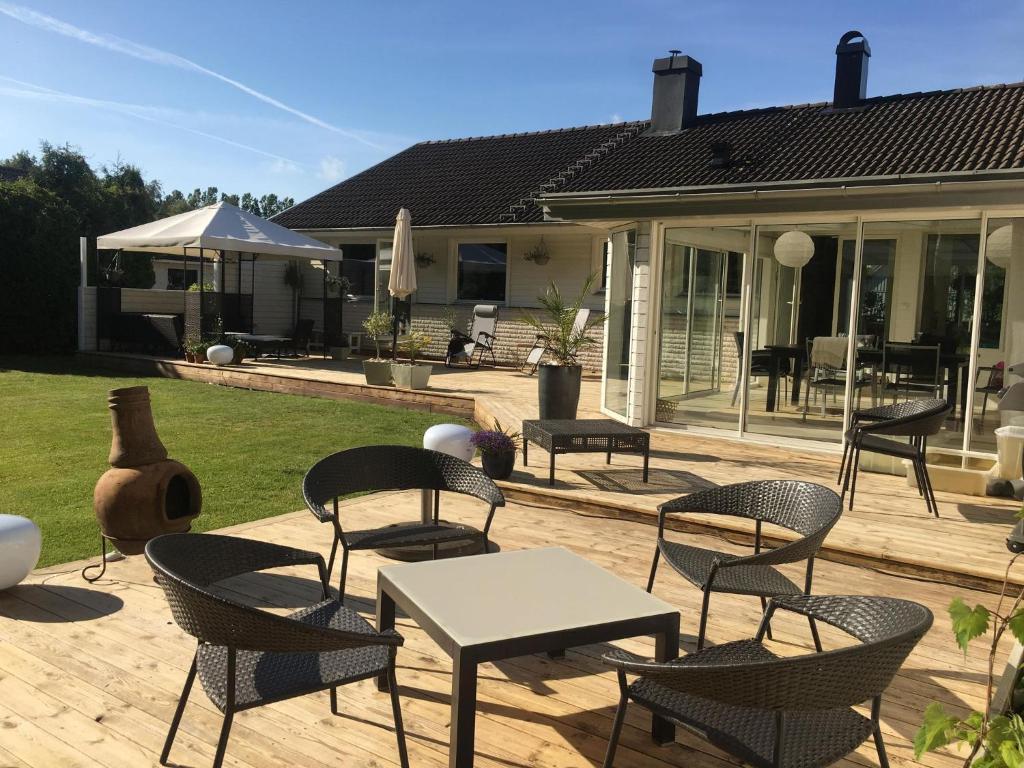 un patio con sillas y mesas en una terraza en Rymlig villa med närhet till Tylösand och Halmstad GK, en Halmstad