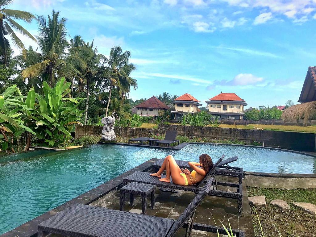 a woman laying on a bench next to a swimming pool at Ubud Rice Field House in Ubud