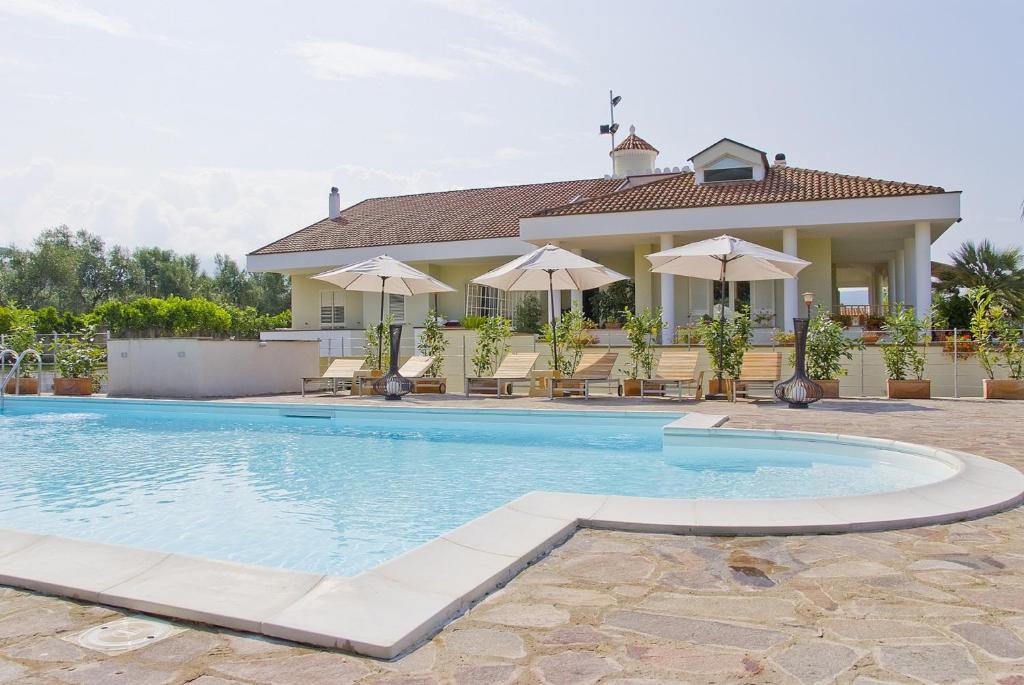 a swimming pool in front of a house with umbrellas at Villa Liberti in Castellabate