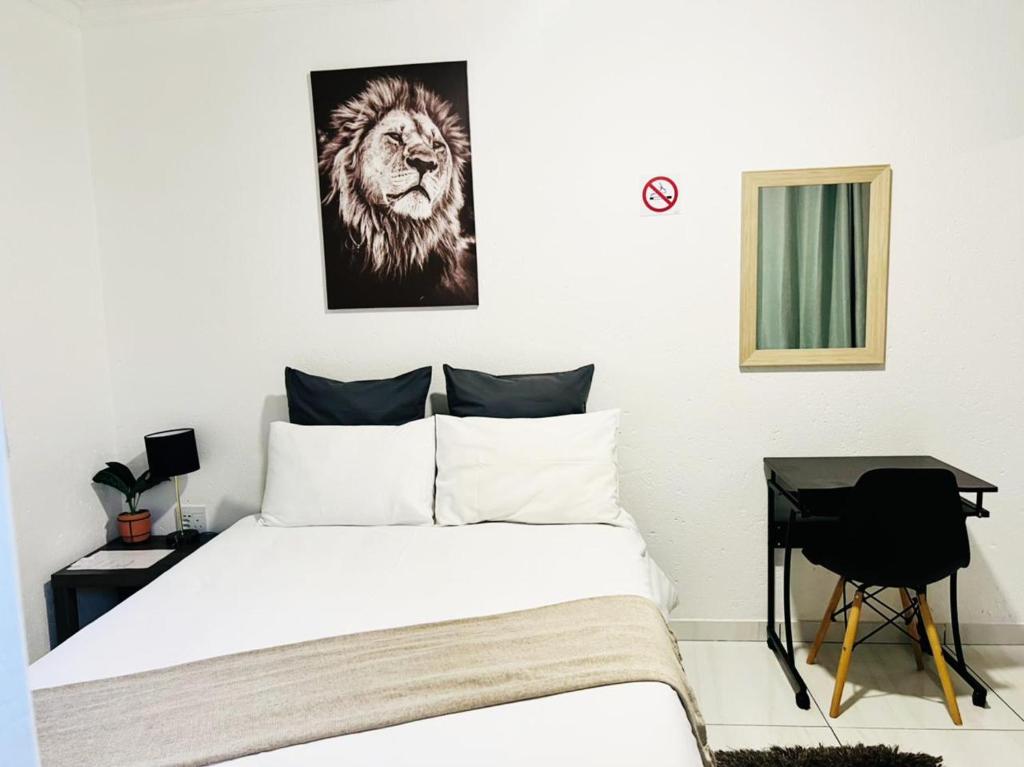 1 dormitorio con 1 cama con una foto de león en la pared en Zindiza Guesthouse en Witbank