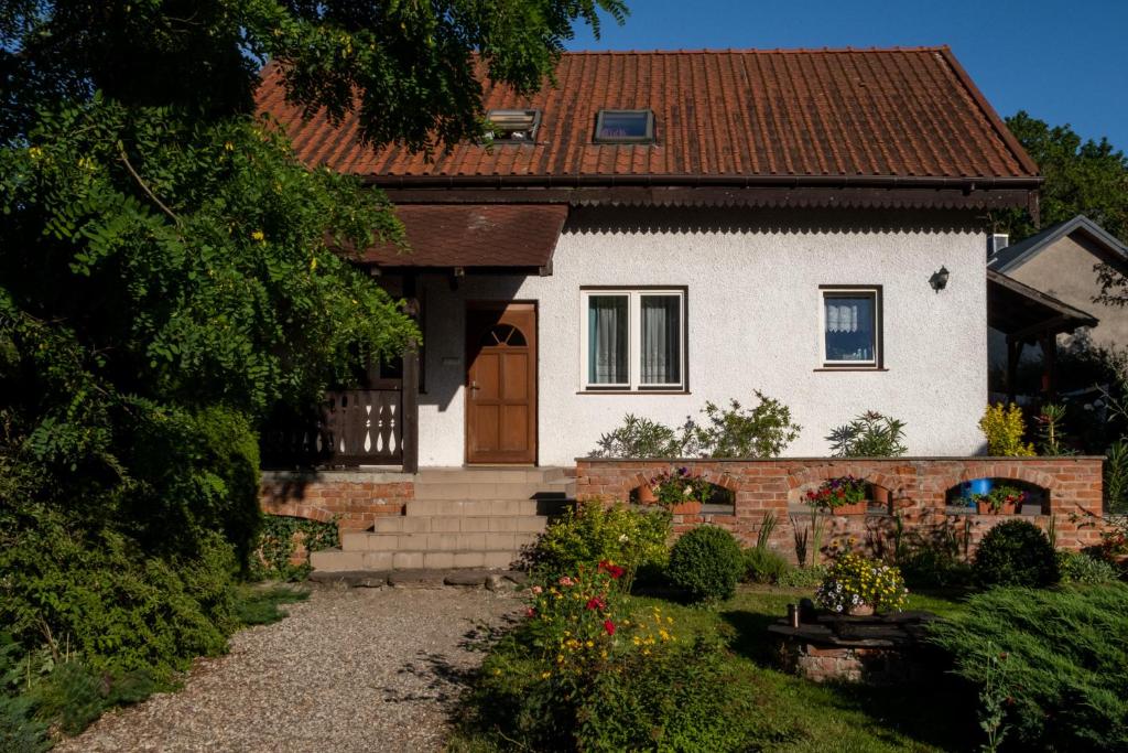 a white house with a brown door and a yard at Dom na Mazurach Gąsiorowo in Purda