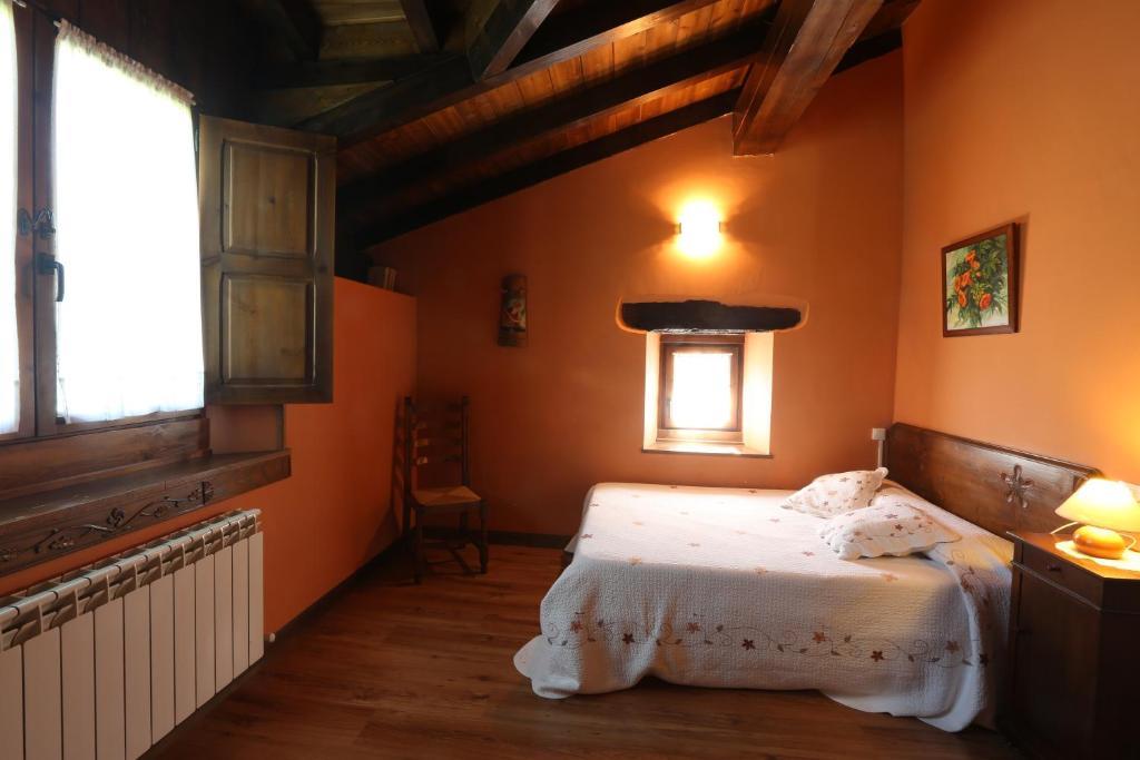 1 dormitorio con paredes de color naranja, 1 cama y ventana en Apaiolarre, en Zuaztoy de Azpilcueta
