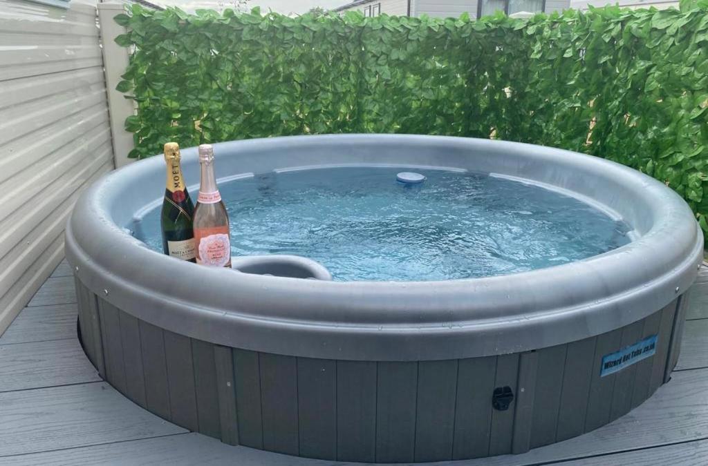 a hot tub with two bottles of wine in it at The Wardens Escape - Tattershall Lakes Country Park in Tattershall