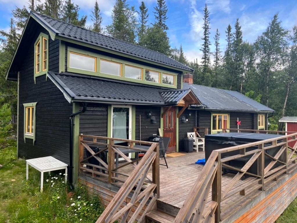 a black tiny house with a large deck at Mysig fjällstuga med direktanslutning till fjället in Oviken