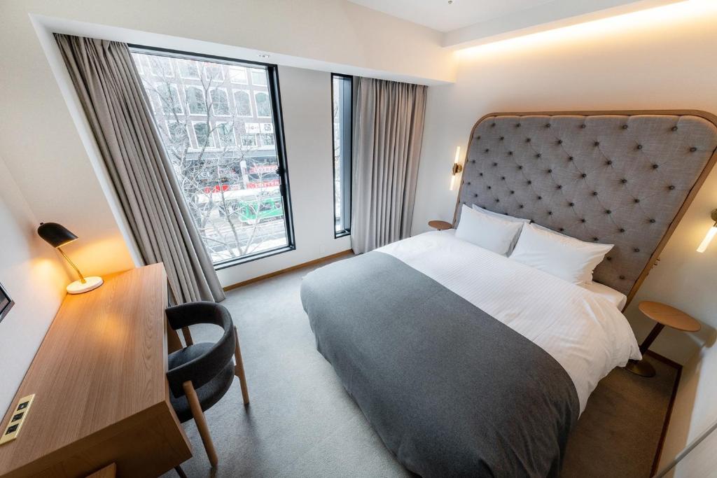 a hotel room with a bed and a desk and window at The knot Sapporo - Vacation STAY 96399v in Sapporo
