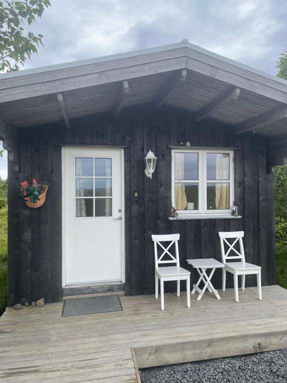 Cabaña pequeña con 2 sillas y puerta blanca en Hulduhólar Cabin - The Elf Hills., en Selfoss