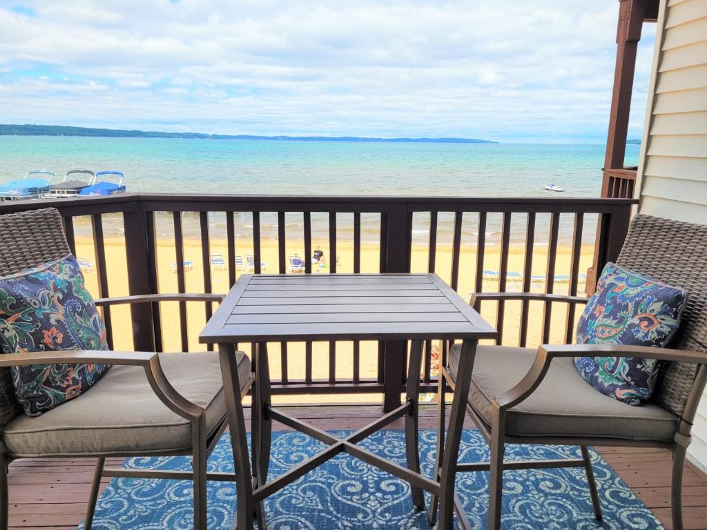 a table and chairs on a balcony with the beach at Beachside 213 with Pool Hot Tub and Private Deck overlooking East Bay in Traverse City
