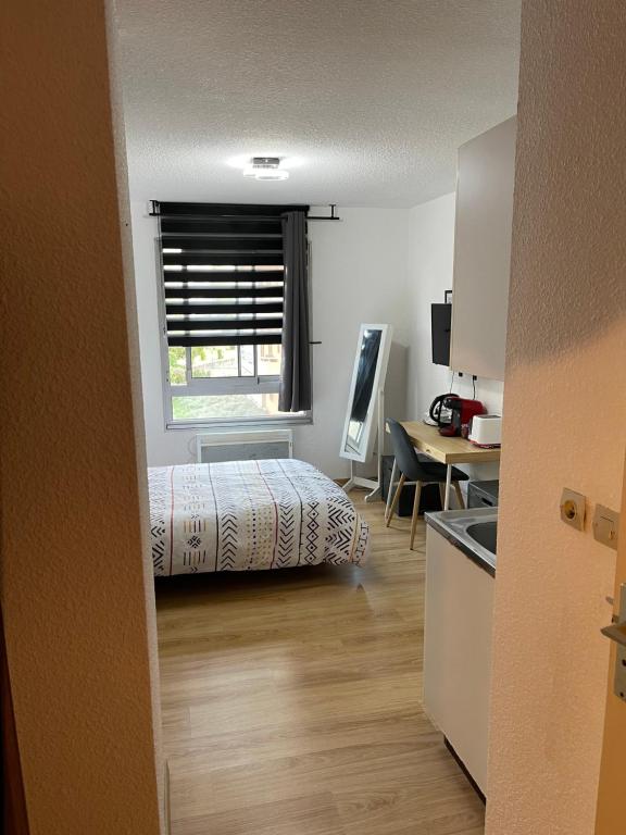 a bedroom with a bed and a desk and a window at Les Logis de Paray Appartement 202 in Paray-le-Monial