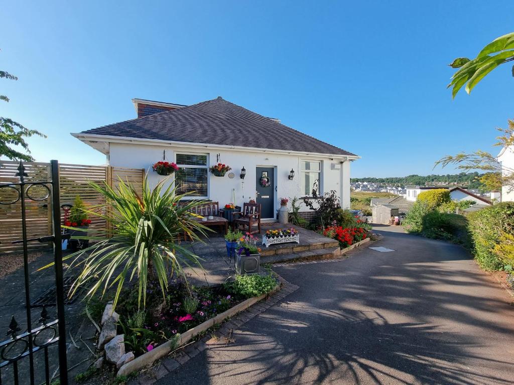 a small white house with a garden in front of it at Lovely private studio room with own kitchen and bathroom. Set in the popular area of Shiphay in Torquay and only a short walk from Torbay Hospital in Torquay