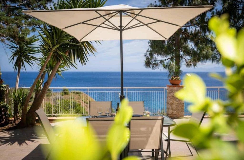 a patio with a table and an umbrella and the ocean at Villa's apartment on the beach, swimming pool A/C in Palermo