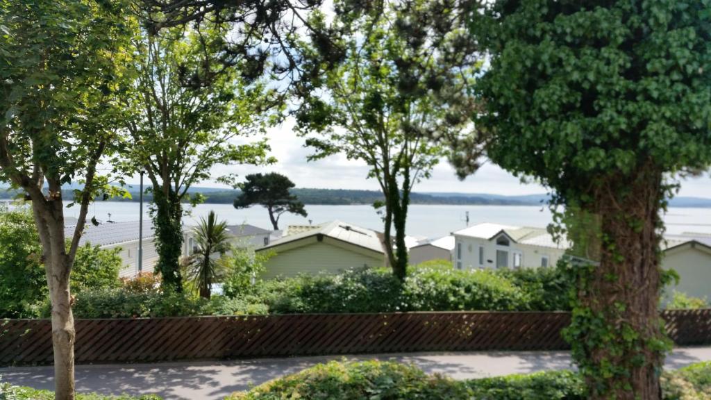 een uitzicht op het meer door de bomen bij Pine Ridge 59 Rockley Park Poole with sea view sleeps six in Poole