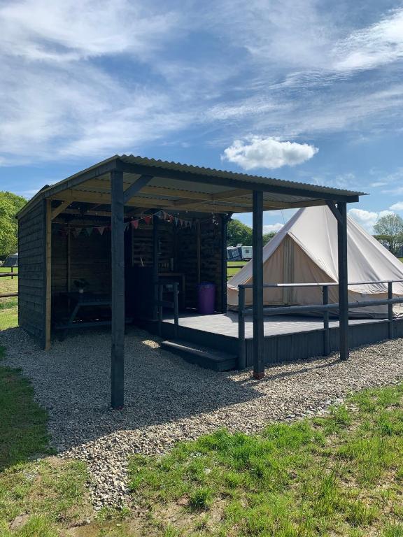 a building with a tent in a field at Bell tent 3 Glyncoch isaf farm in Llwyn-Dafydd