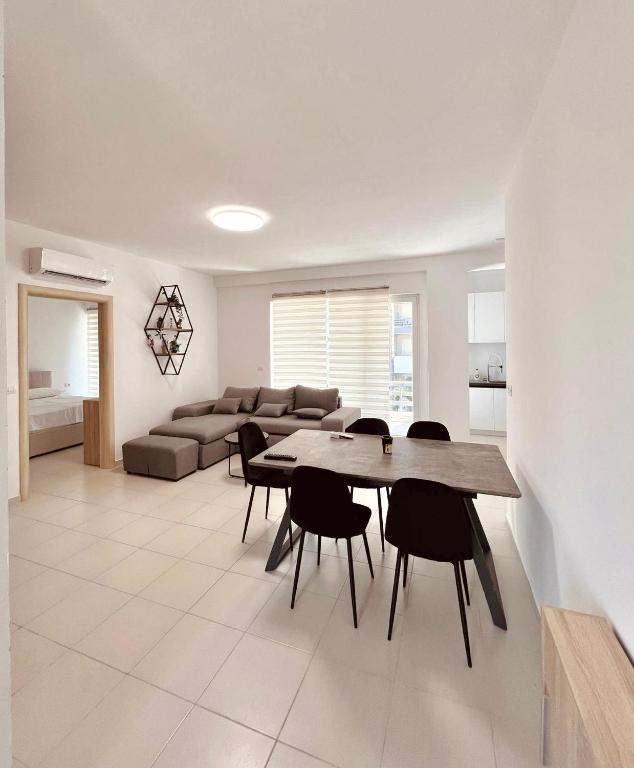 a living room with a table and chairs and a couch at Pine Breeze Apartment Gjiri i Lalezit in Draç