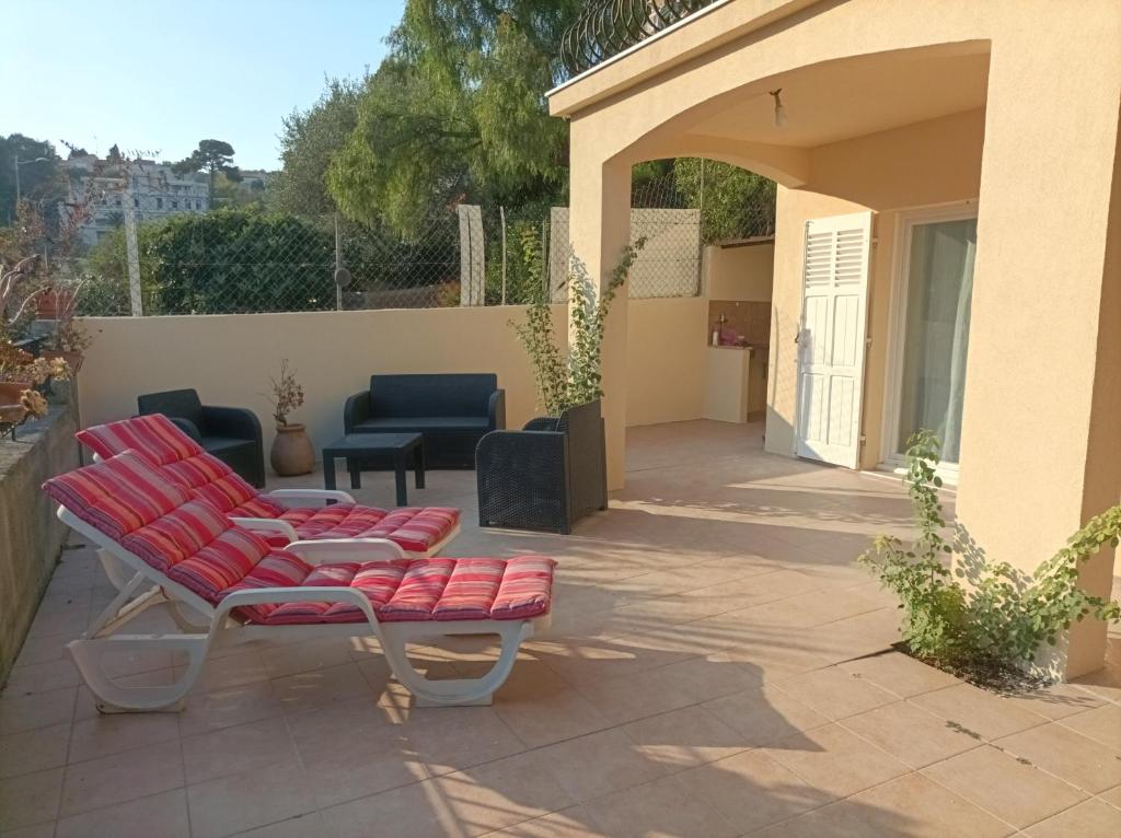 eine Terrasse mit roten Stühlen und einem Sofa in der Unterkunft Très bel appartement entier proche de la mer 2 chambres 1 salon in Vallauris