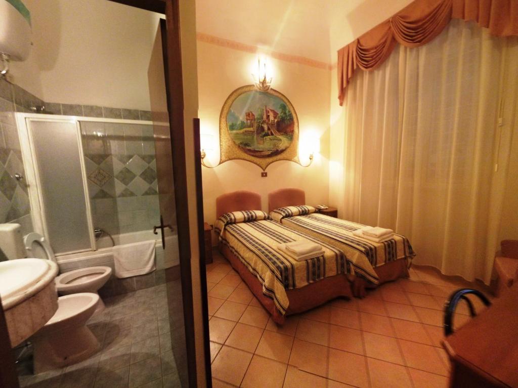 sypialnia z łóżkiem oraz łazienka z umywalką w obiekcie Cambridge Hotel w Rzymie