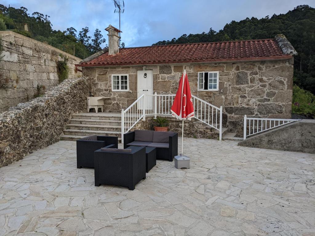 a stone house with a red umbrella in front of it at A Casa do Río Bueu in Bueu