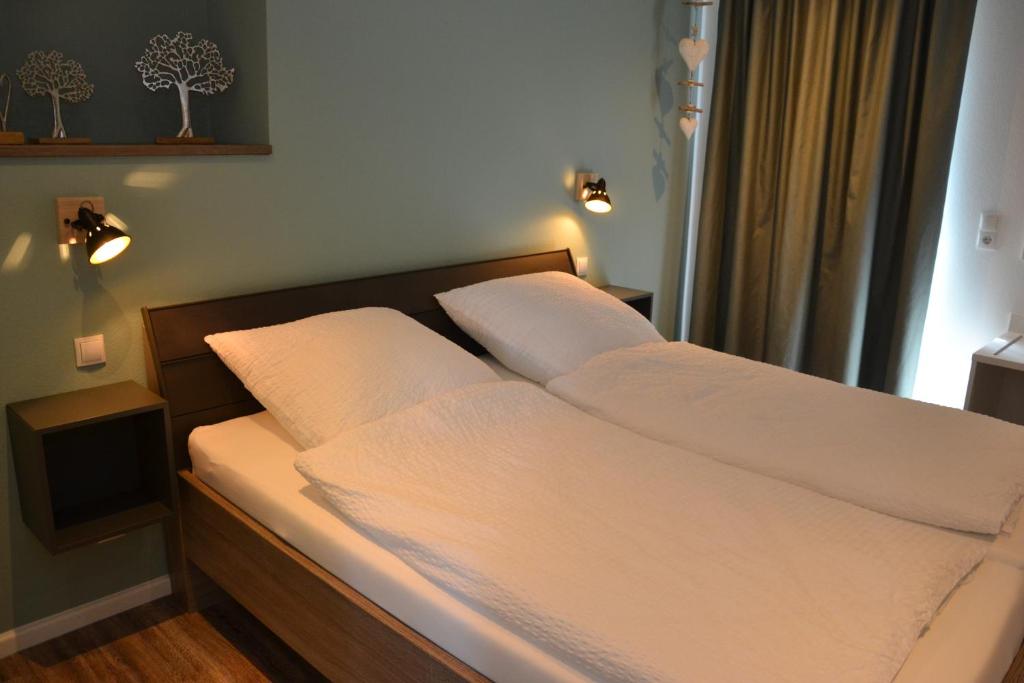 ein Bett mit weißer Bettwäsche und Kissen in einem Schlafzimmer in der Unterkunft Gasthof Zumdohme in Lastrup