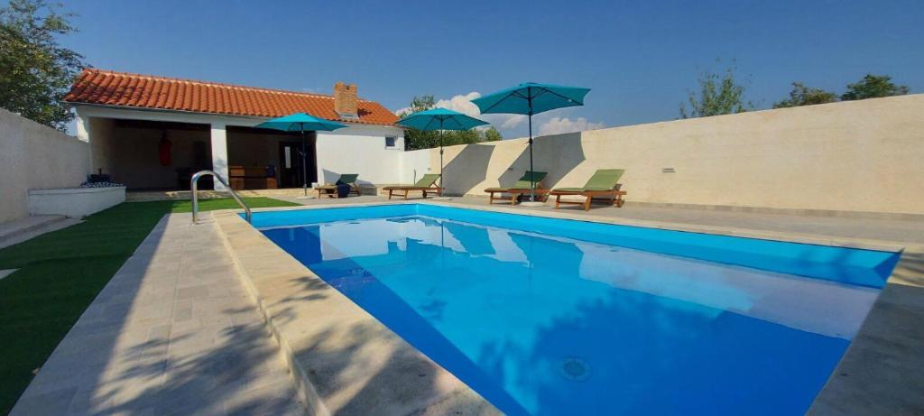 a swimming pool with blue water in front of a house at Holiday Home Mary with Pool in Rupalj