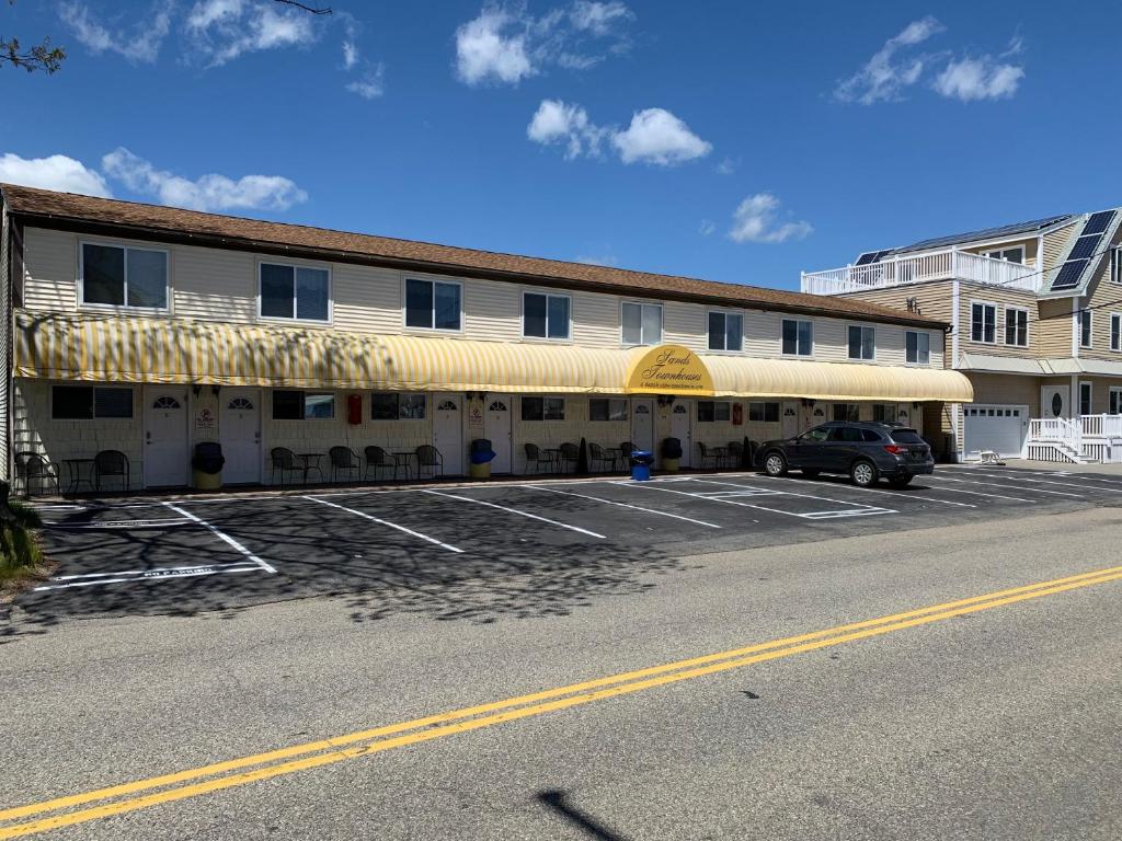 a building with a car parked in a parking lot at Sands Townhouses in Old Orchard Beach