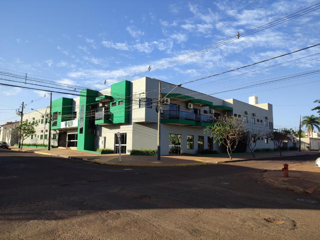 un edificio blanco y verde en una esquina de la calle en Hotel Campo Verde, en Dourados