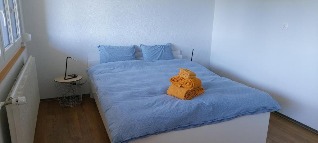 ein kleines Schlafzimmer mit einem Bett mit blauer Bettwäsche in der Unterkunft Chambre d'hôte L'optimisme in Montfaucon