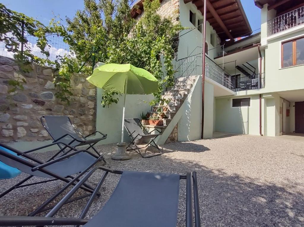 twee stoelen en een paraplu naast een gebouw bij Corte Vezzola bilocale Emma in Puegnago