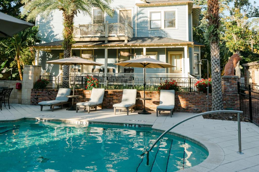 una piscina con sillas y sombrillas frente a una casa en The Collector Inn (Adults Only) - Saint Augustine, en St. Augustine