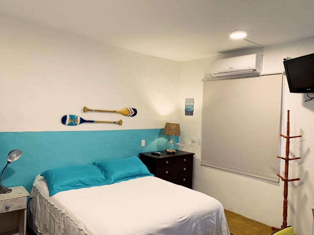 Un dormitorio con una cama con una pared de acento azul en Apartamento Centro Histórico - Vila- Ilhabela, en Ilhabela