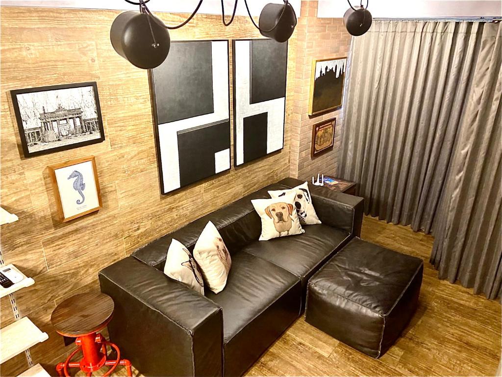 a living room with a black leather couch at Saint Moritz Flat Particular com Garagem, Estilo Industrial no Coração de Brasília in Brasilia
