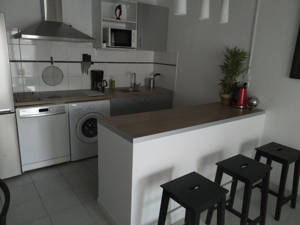 cocina con fregadero y encimera con taburetes en A Poitiers, 2 chambres, très bel appartement de 65 m2 en Poitiers