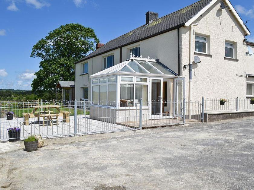 a white house with a fence in front of it at Cob Cottage in Tregaron