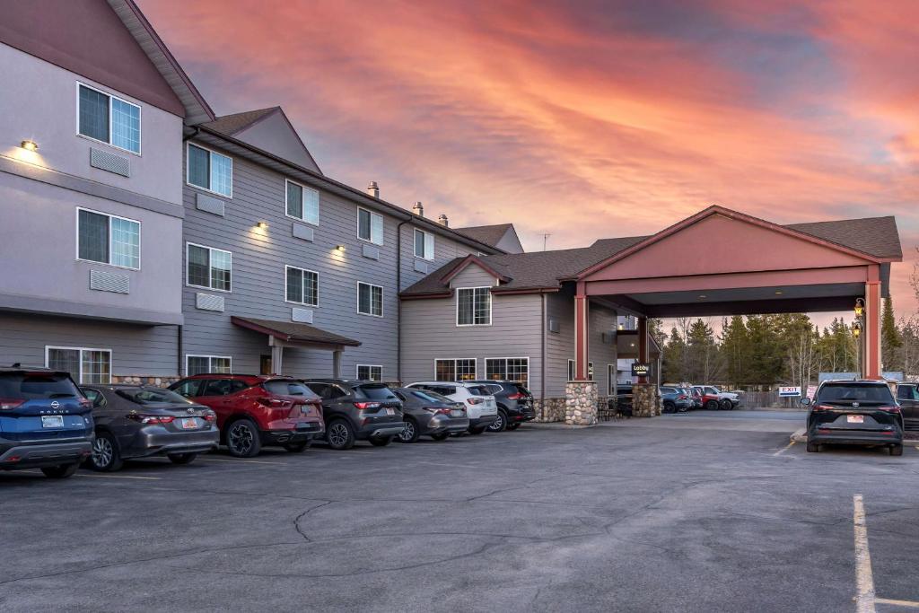 un estacionamiento con autos estacionados frente a un edificio en Best Western Desert Inn en West Yellowstone