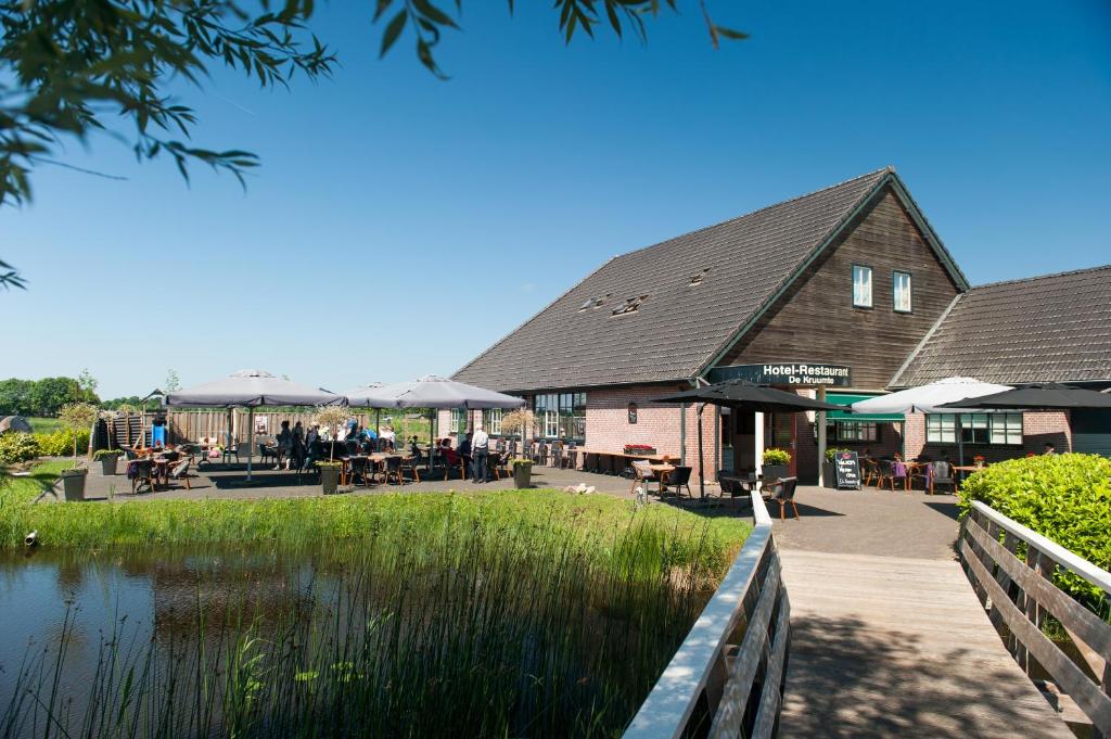 ein Gebäude mit Tischen und Stühlen neben einem Wasserkörper in der Unterkunft De Kruumte in Giethoorn