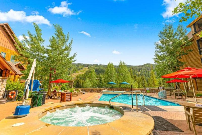 a large swimming pool in a yard with umbrellas at 1 Bedroom Mountain Condo In River Run Village With Beautiful Mountain Views And Walking Distance To Ski in Keystone